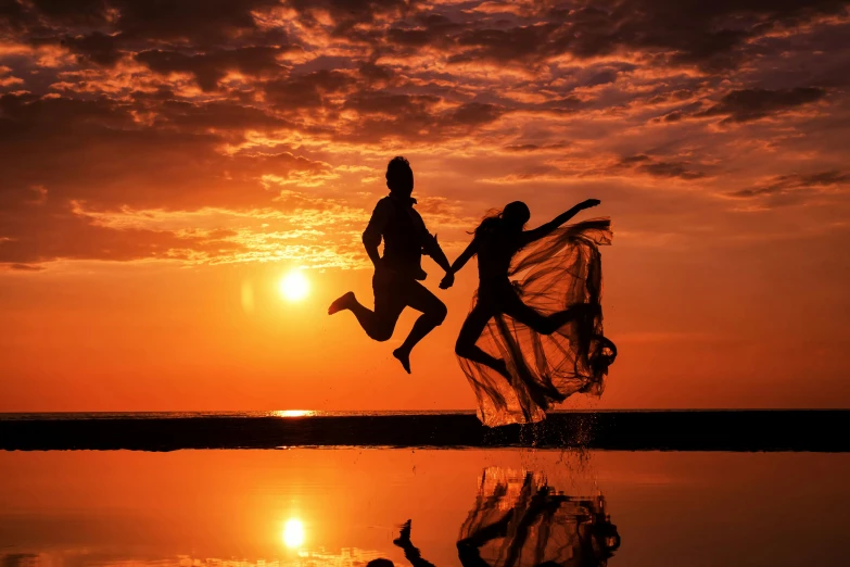 two people are running towards the ocean at sunset