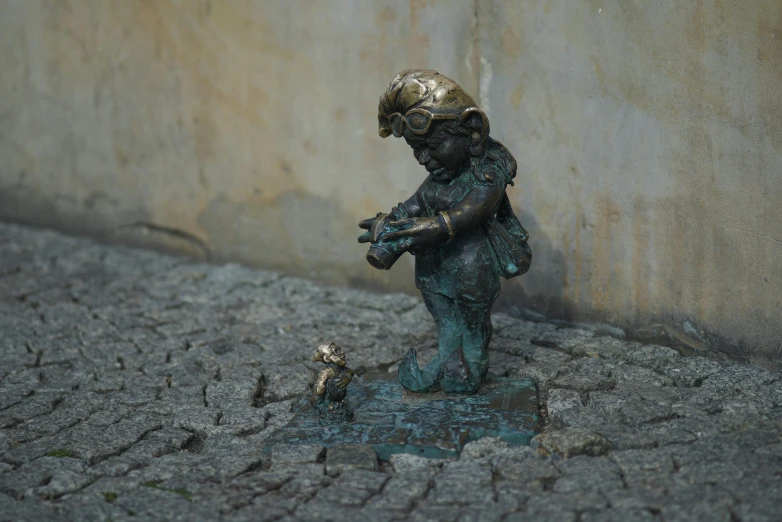 small bronze statue of a girl in an area with bricks