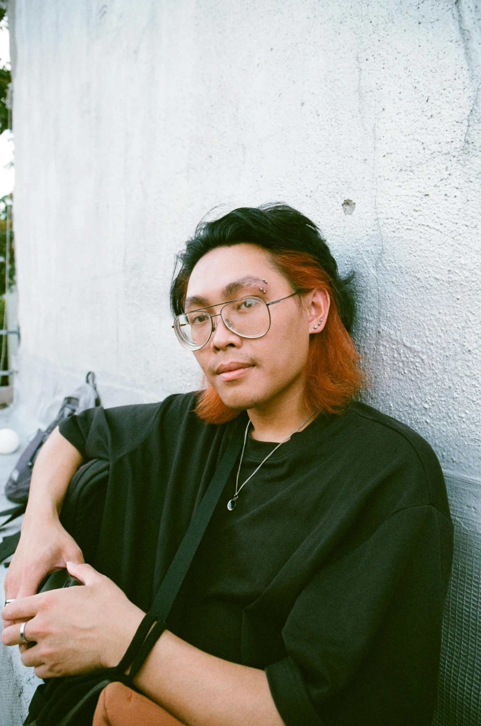 a man with red hair is leaning against a wall with his arms folded