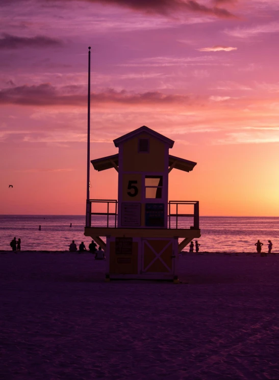a life guard tower stands on the beach at sunset