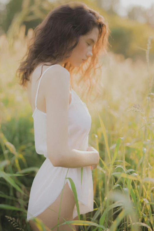 a woman with brown hair standing in tall grass