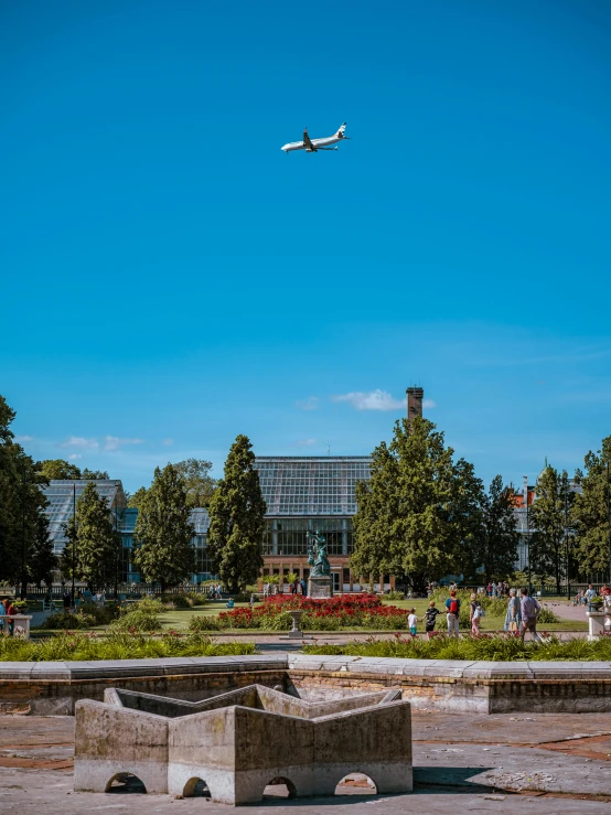 an airplane flying overhead above a park like setting