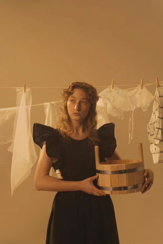 the woman is holding a basket with clothes hung up to dry