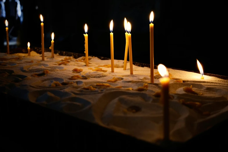 several lit candles on a cake in the dark