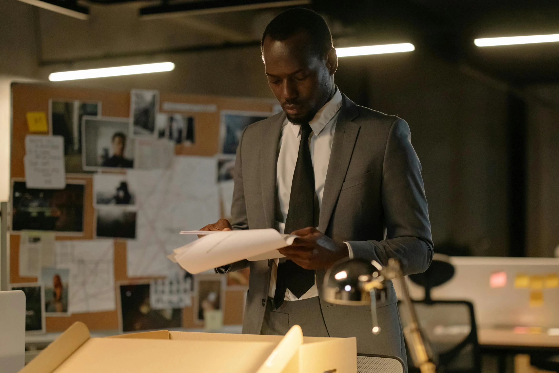 a man holding a piece of paper standing next to a desk