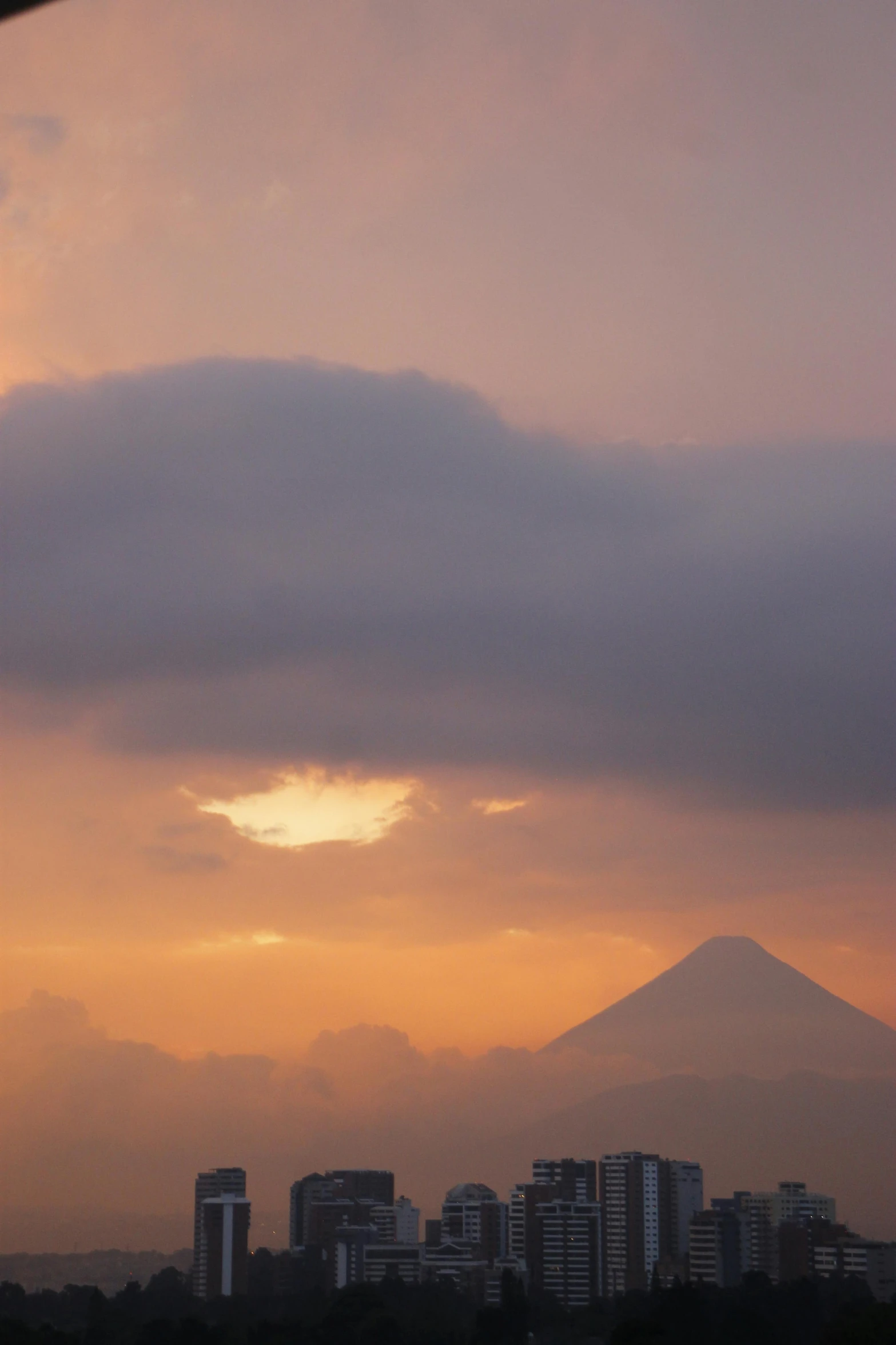 a cloudy sky over the city and mountain