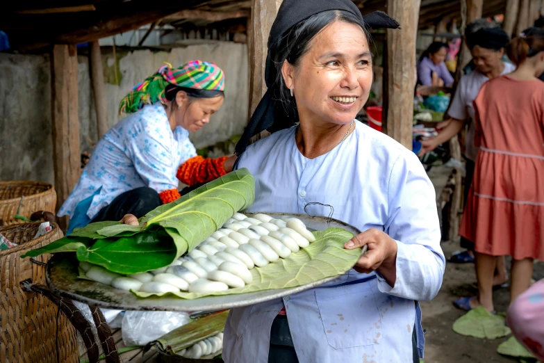 a woman carrying plates of corn with two women working