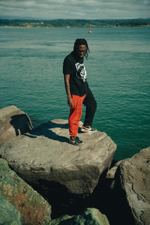 a young man is standing on a rock in the water