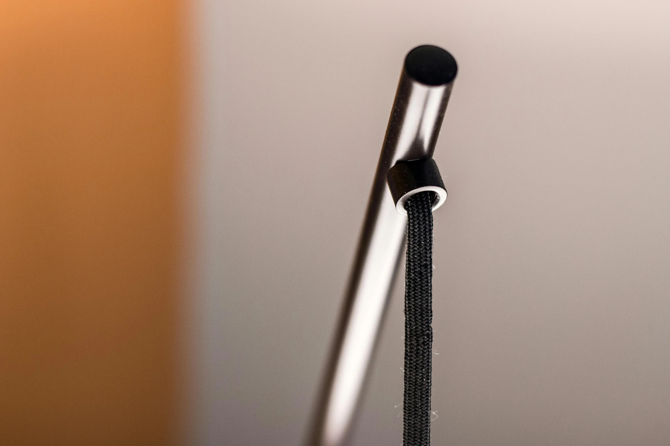 a silver pen resting on a desk with a wooden surface