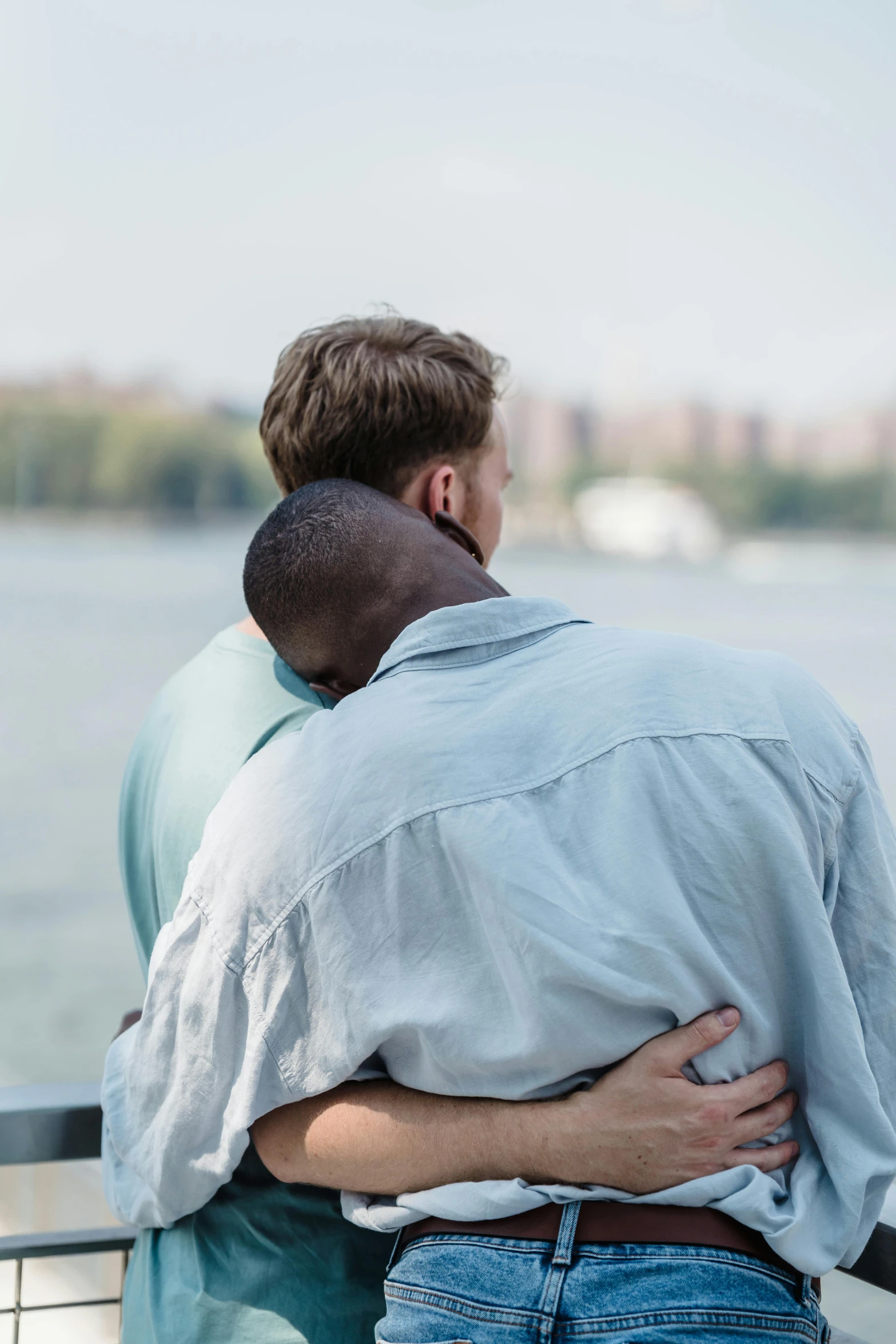 a man hugging a person with a lake behind him