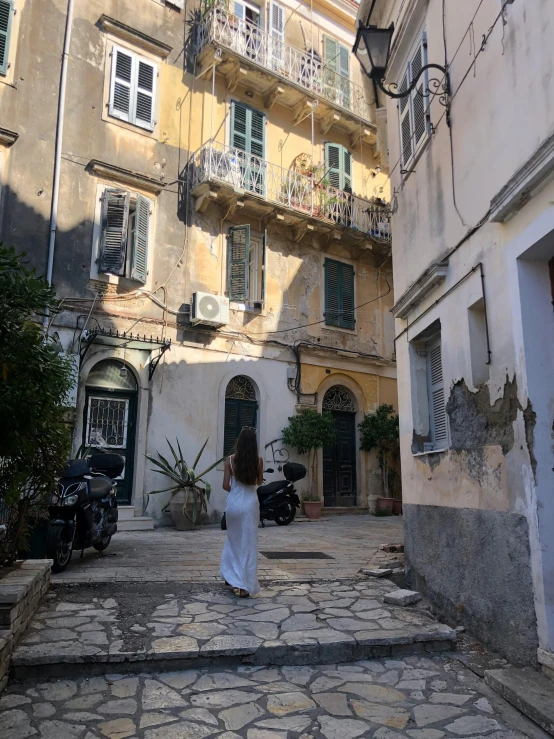 a woman walking down a stone courtyard under several balconies