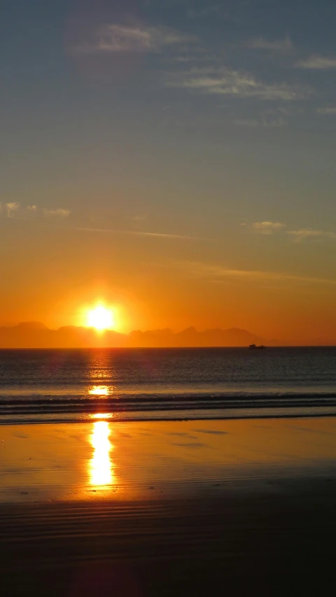 the sun is setting on a beach near the water