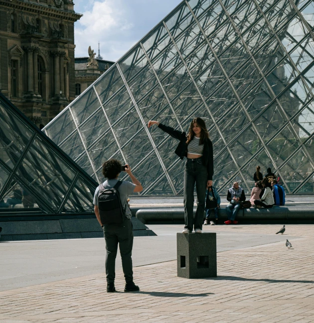 a woman is standing on a pedestal by a pyramid