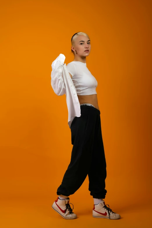 a woman with white top standing next to orange wall