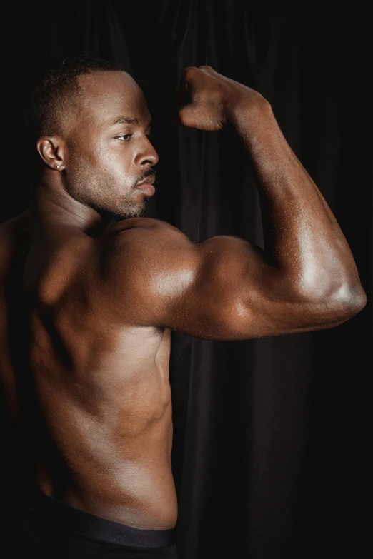 a shirtless man posing with his arm crossed in the dark