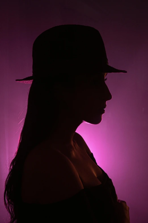 a young woman standing with a hat on and long dark hair