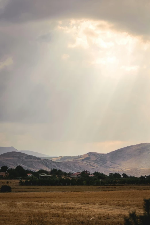 a scenic view of a mountains range and countryside under a cloud filled sky