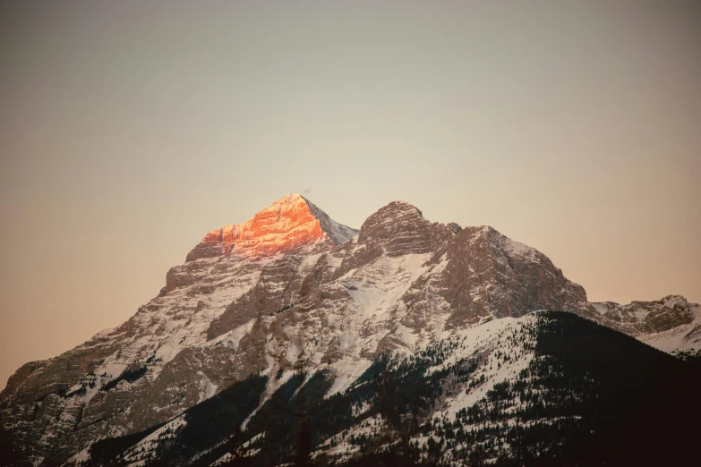 the snow covered mountains with one red peak