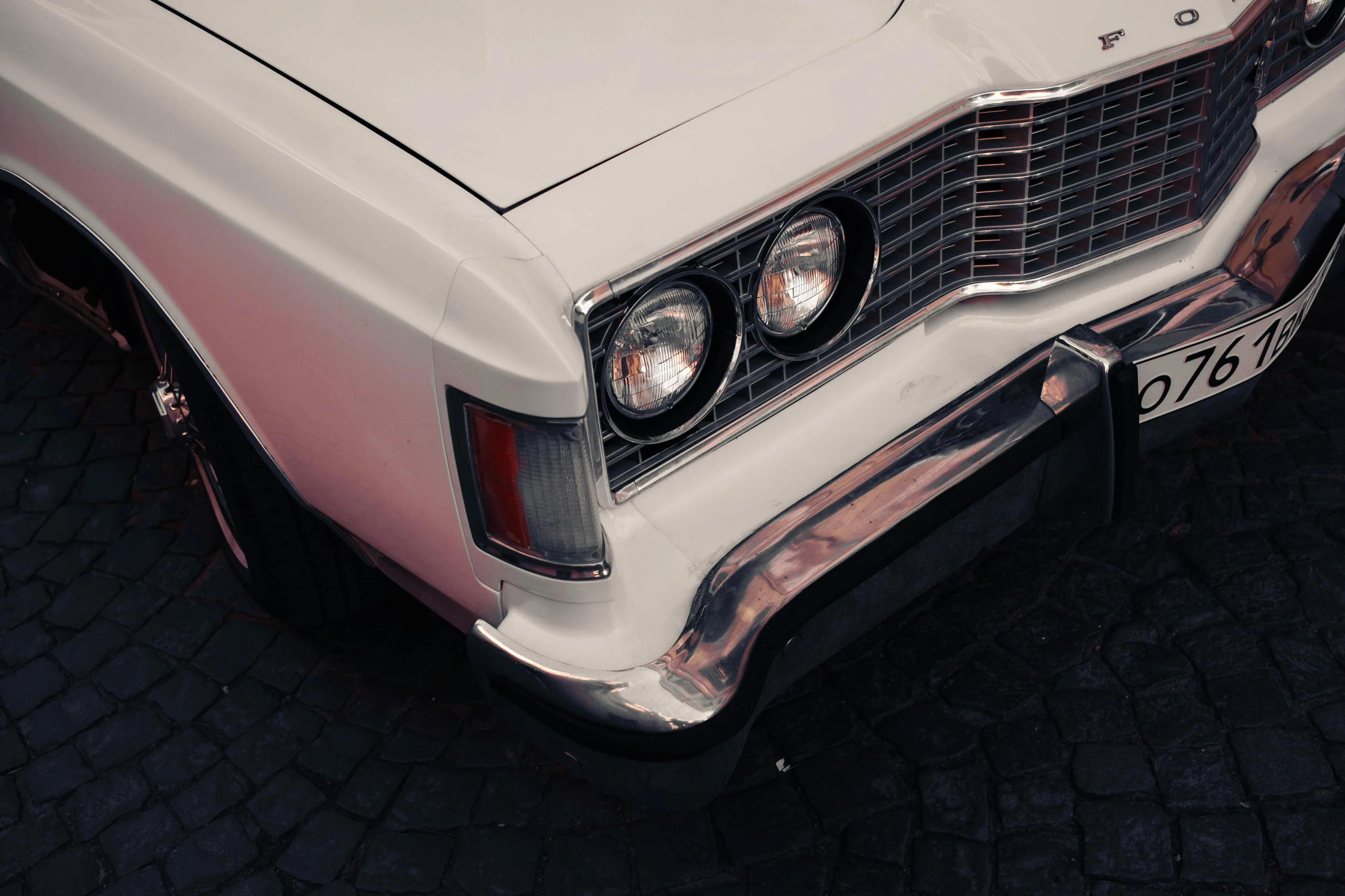 an old style white car parked in the street