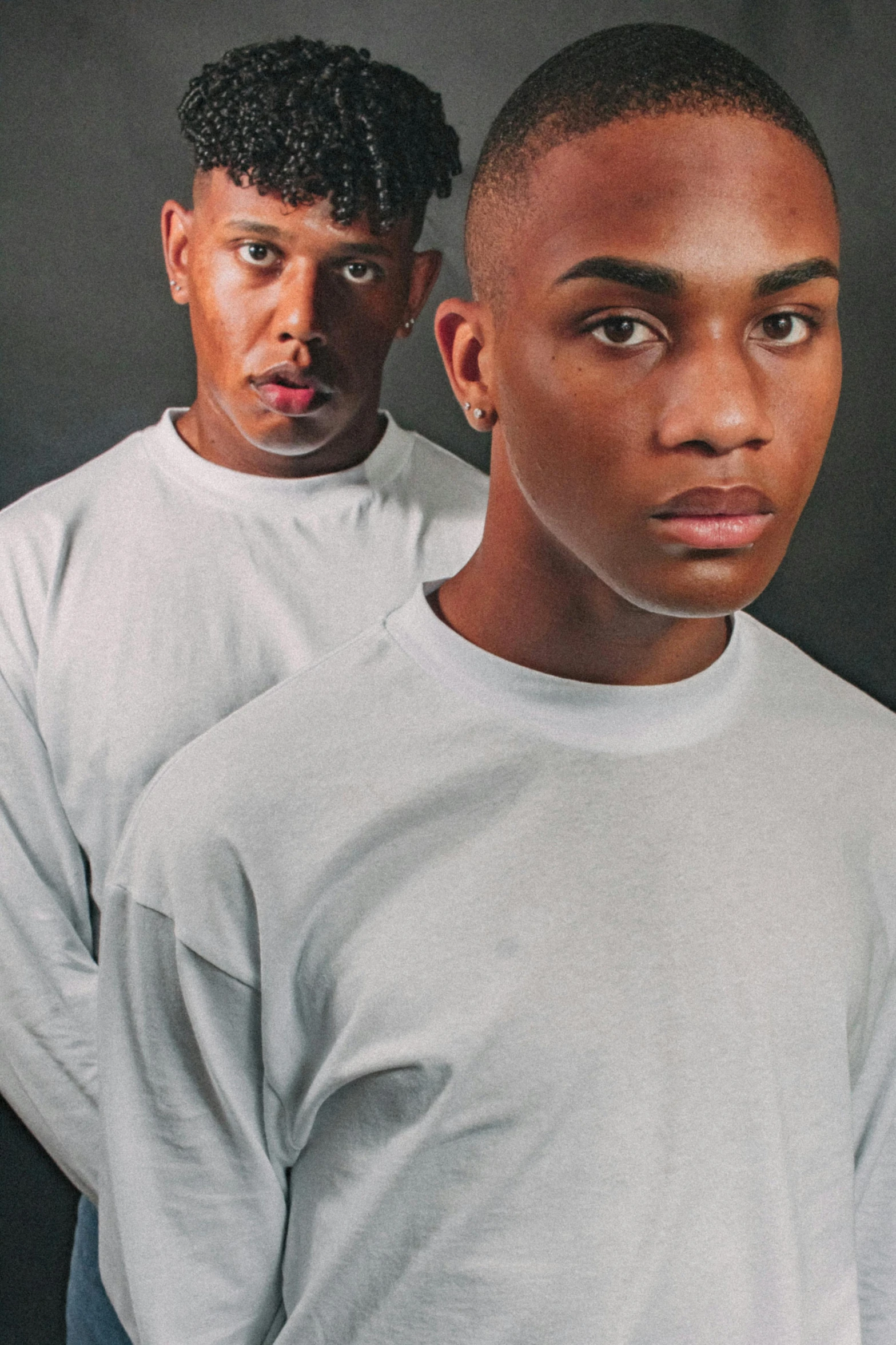 the two men pose for a portrait in front of black backdrop