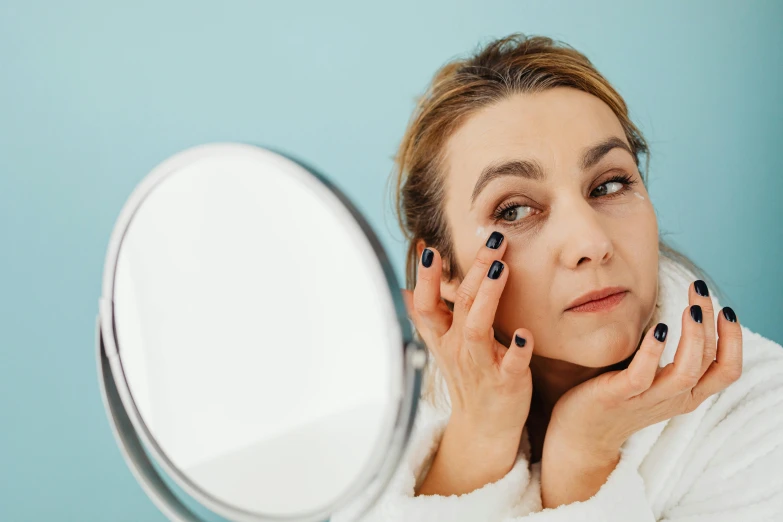 a close up of a woman with makeup looking at herself in the mirror