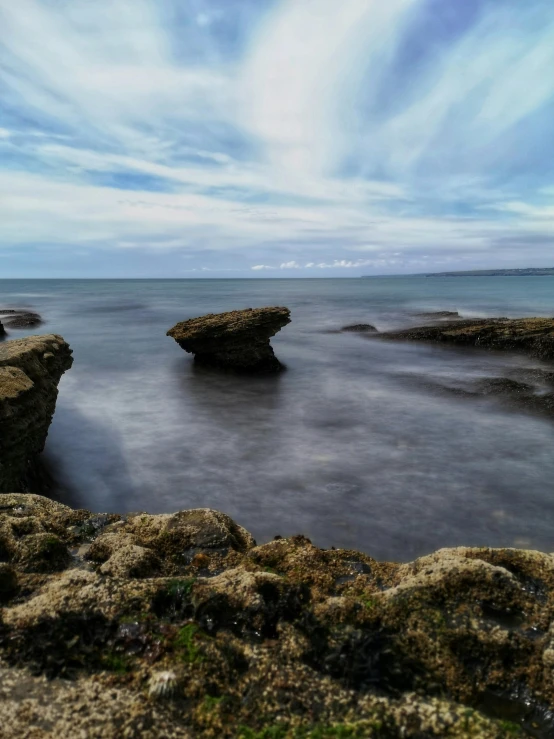 rocks in the water and grassy rocks sticking out of it