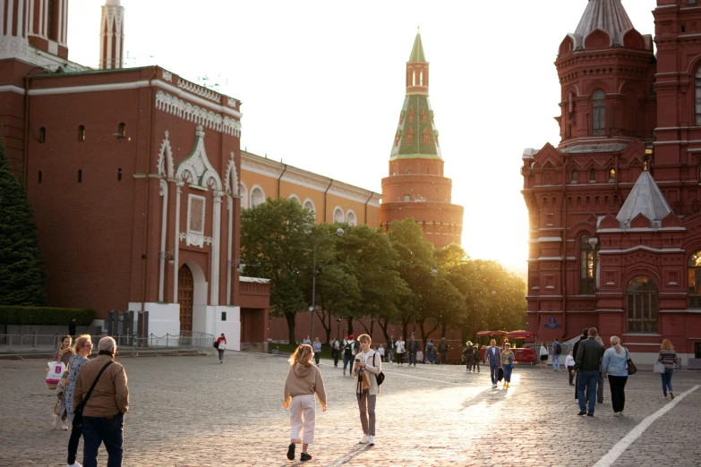 a group of people walking across a brick street next to tall buildings