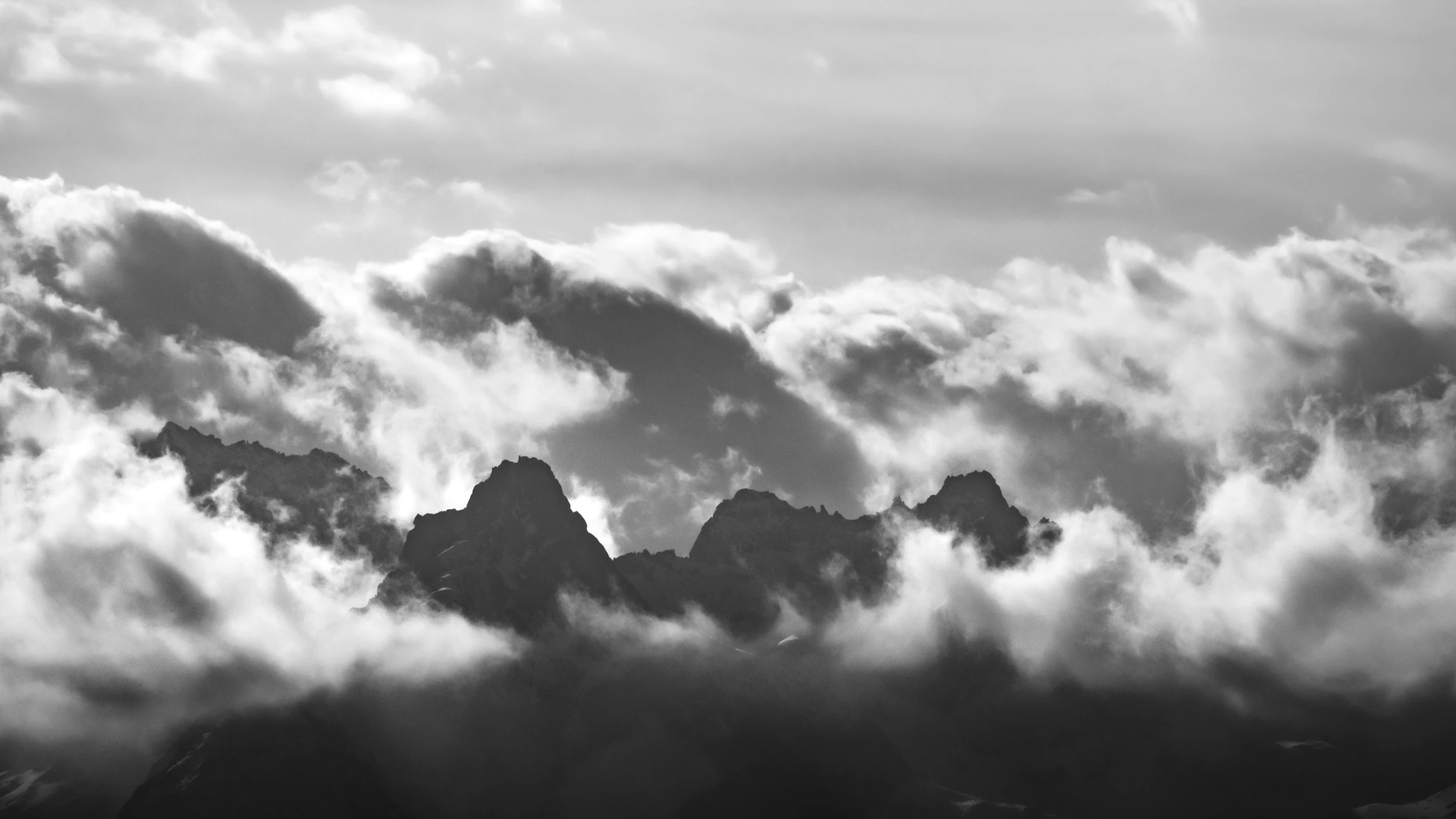 black and white po of mountains in the distance covered by clouds