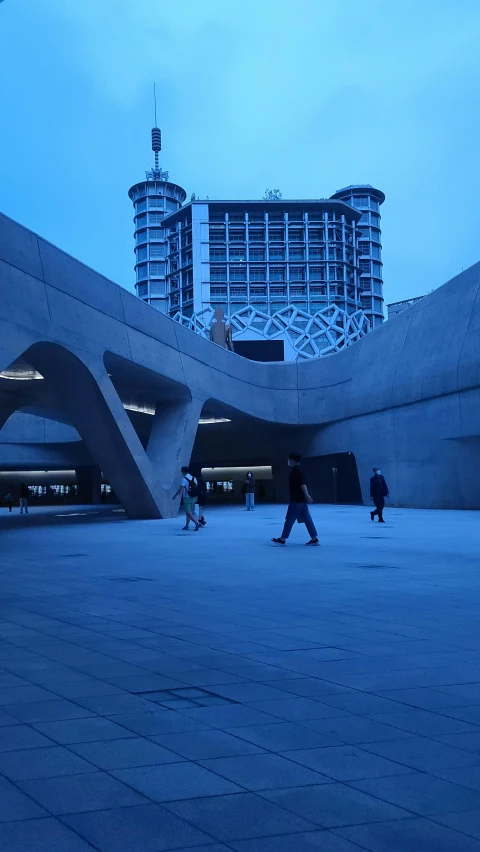 several people walking in a courtyard with a building in the background