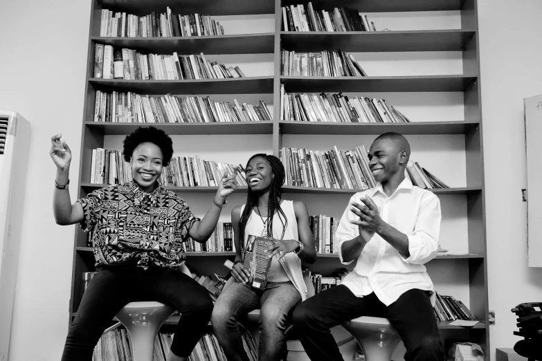 a man sitting on a desk with two women next to him