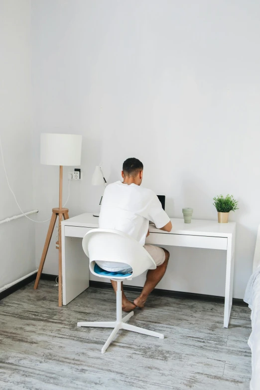 the man is sitting in the chair at the computer desk