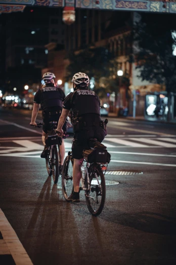 two people in helmets riding bikes down a city street