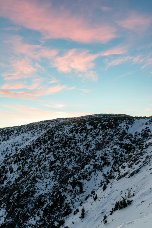 a person skiing on a snow covered slope with the sky covered in clouds