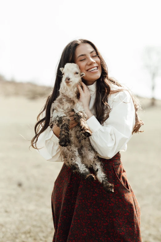 a woman in a dress holding a dog in her hands