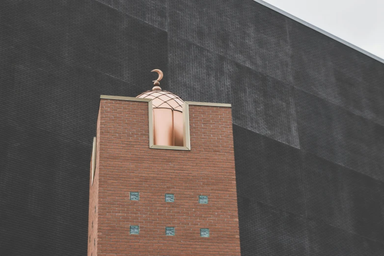 the top of a brown brick building with an interesting window on it