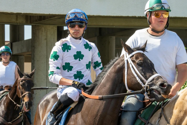 two jockeys sit on horses as the rest walk away