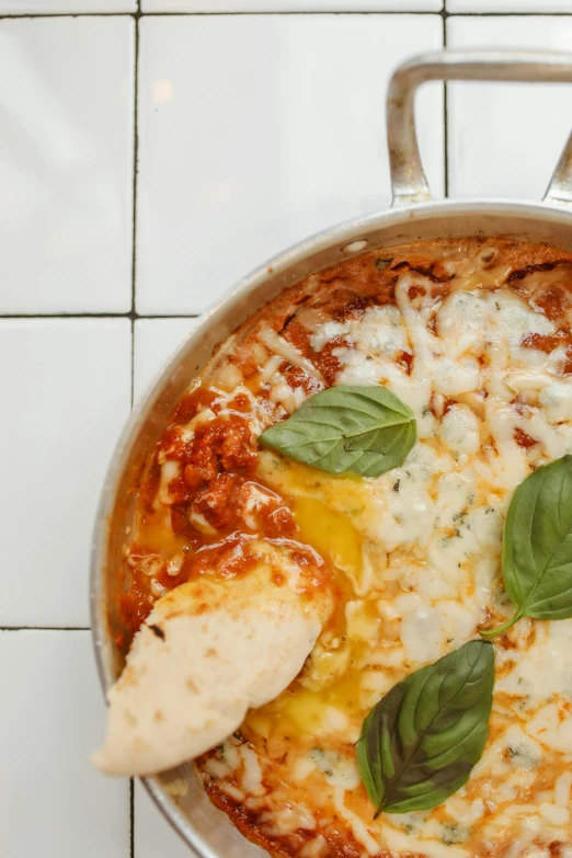 a pan of cheese pizza on top of a tiled floor