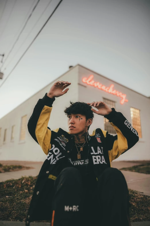 young person sitting on street corner holding up a cup