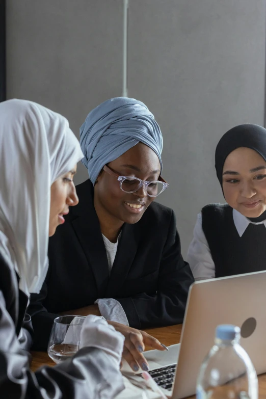 a group of people sitting at a table looking at a computer