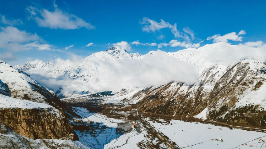 a landscape shows snow - covered mountains, a river and snow - capped peaks