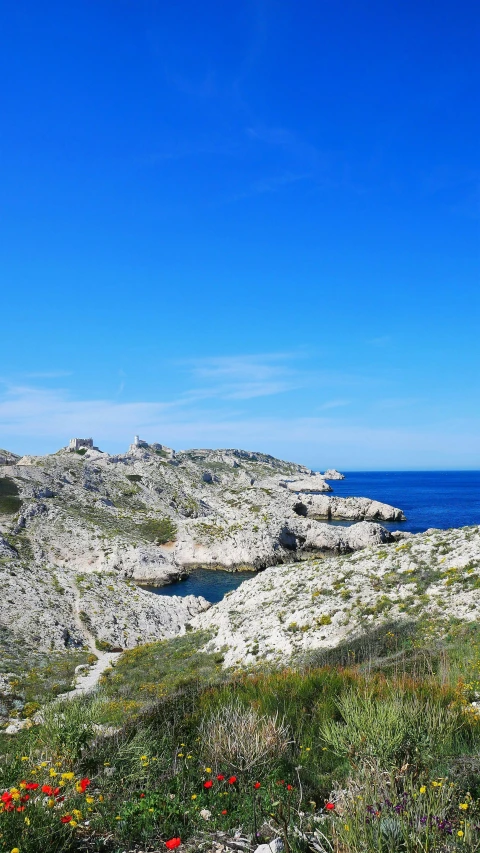 an island and rock outcroppings on the edge of a blue ocean