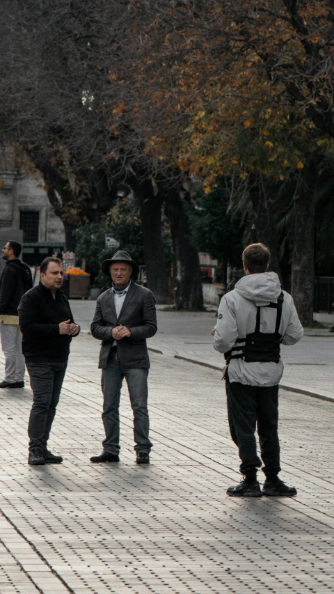 three guys standing in a plaza outside on their cell phones
