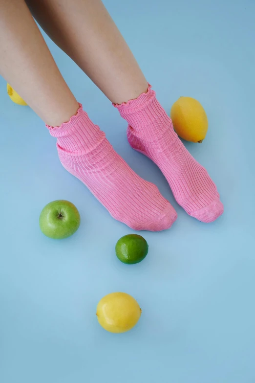 a pair of pink socks with green apples and lemons