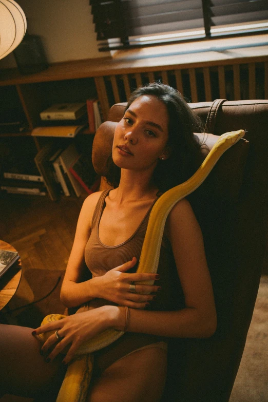 a woman sits in a chair holding a banana