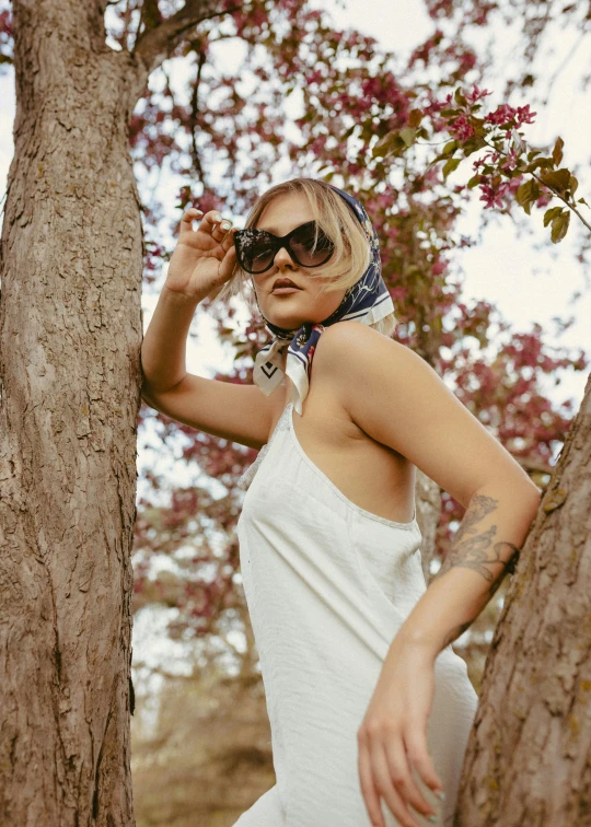 woman in dress standing near trees wearing sunglasses