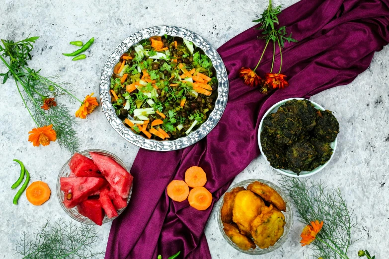 a group of bowls of food on a purple blanket