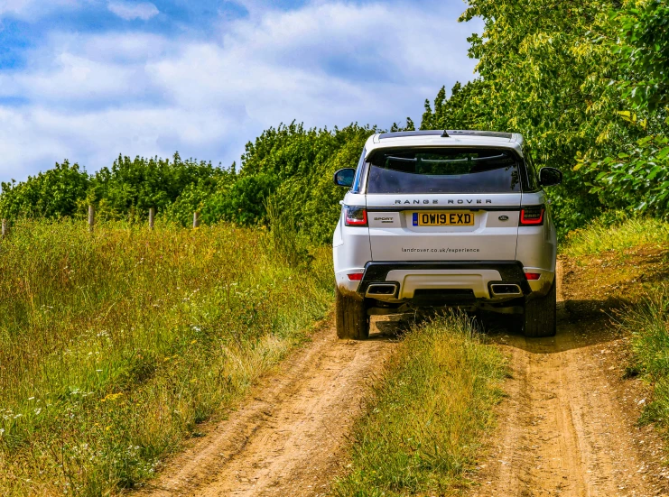 the suv is parked in a rural area near some trees