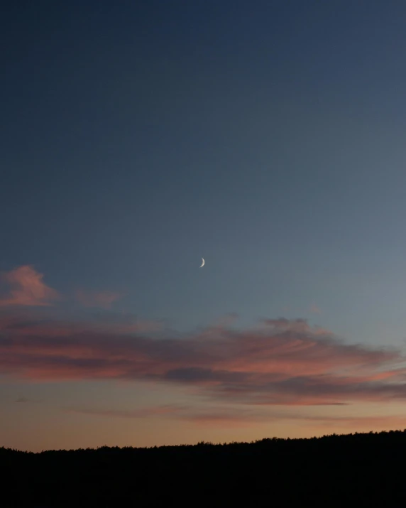 a clear full moon is seen above the hills