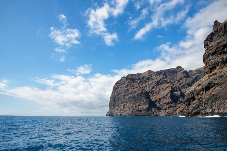 a boat that is on the water by a cliff