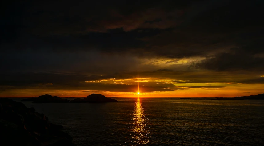 a sunset seen from the shore near some small islands